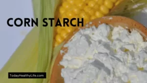 A cup of cornstarch with raw corn in the background. What does eating cornstarch do to your teeth?