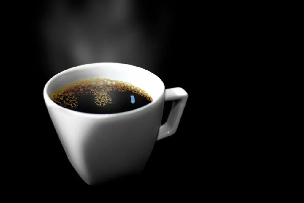A cup of enzyme coffee for weight loss with a black background.