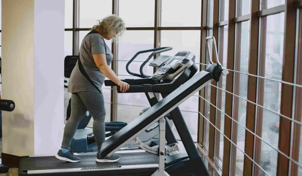 A lady trying to lose weight by using the treadmill in a gym.